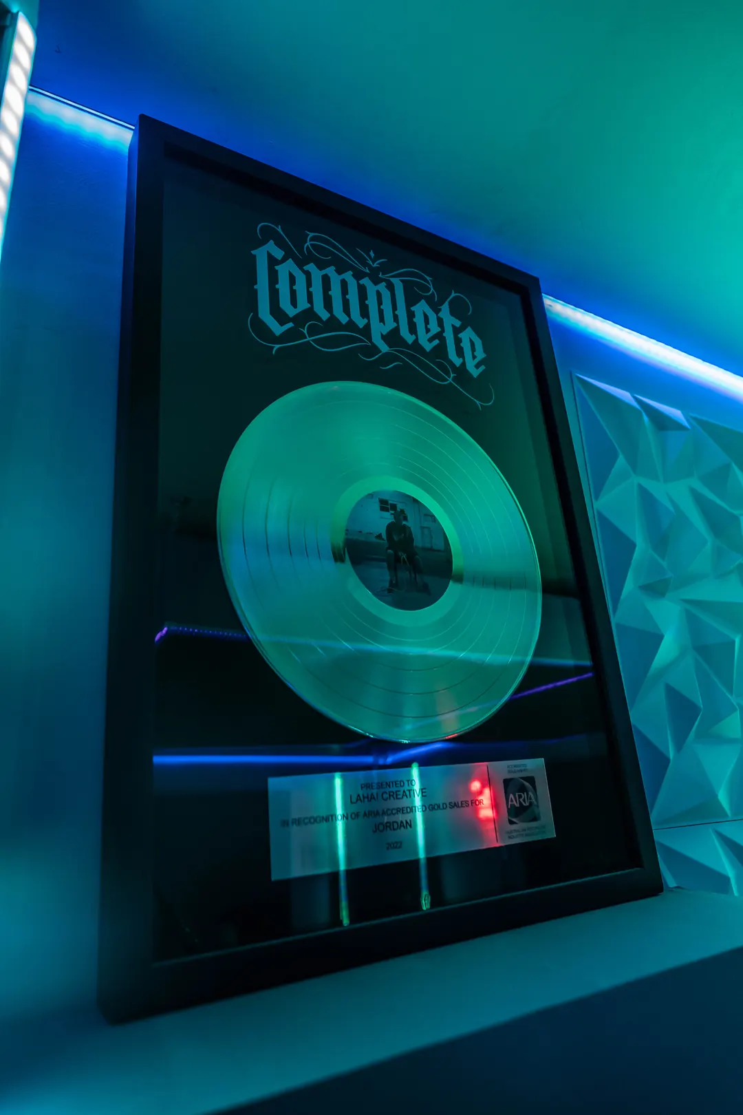 A framed gold record for Complete on the studio wall